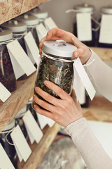 Zielona herbata.Kobieta wybiera rodzaj herbaty podczas zakupów w sklepie herbacianym - obrazy, fototapety, plakaty