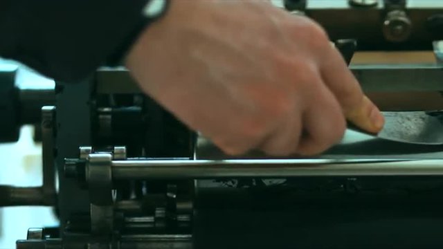 Caucasian male putting ink on a vintage letterpress machine roll. Tracking left to right 4k 60 FPS. Shot with Blackmagic URSA Mini