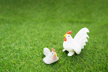 Ceramic chicken couple on green grass / Still life of Ceramic couple of hen and cock chicken doll on green grass