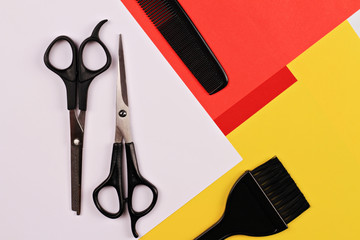 Scissors,comb and brush for hair coloring on on colorful, simple, minimalistic, geometric background. Hairdresser salon concept. Haircut accessories