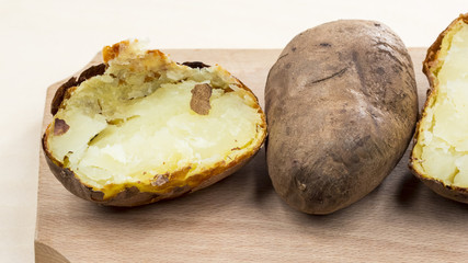 Baked potatoes with shell on a wooden cutting board
