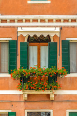 Fototapeta na wymiar Beautiful window decorated with flowers in Italy