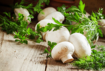 White mushrooms champignons, dill, parsley, old wooden table, ru