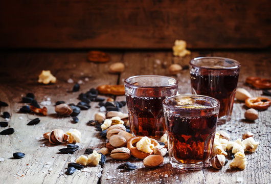 Cola glasses, sweet and savory snacks, old wooden table, unhealt