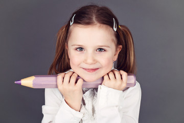 Fototapeta premium Cute young schoolgirl holding a pencil