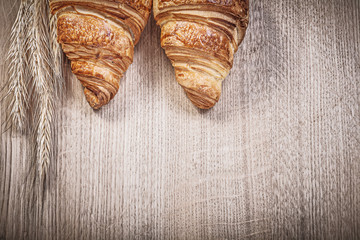 Ripe wheat rye ears newly-baked croissants on wooden board