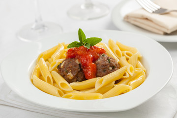 A beautiful plate of Italian penne pasta with meat balls and tomato sauce