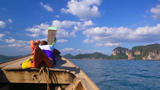 Tourist enjoys a ride on the bow of a traditional Thai long tail boat