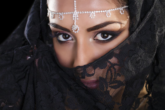Beautiful Woman in Middle Eastern Niqab veil on isolated black b