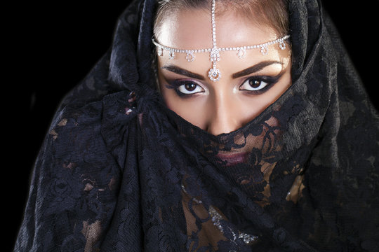 Beautiful Woman in Middle Eastern Niqab veil on isolated black b