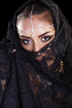 Beautiful Woman in Middle Eastern Niqab veil on isolated black b