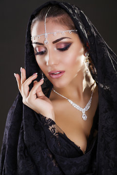 Portrait of a beautiful woman with arabian makeup in black paran