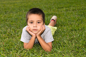 the serious boy lies on a grass