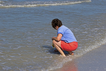 Woman walking on beach collecting seashells