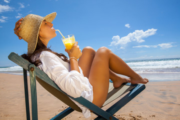 Young woman lying on the beach and refreshing with juice