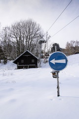 Blue direction traffic sign on end of ski lift in snowy mountains