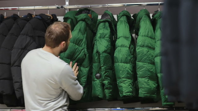 Middle-aged man chooses a warm jacket in store