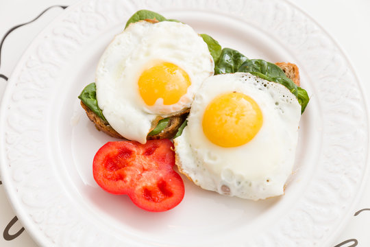 Healthy sandwiches with spinach fried eggs and tomato on a white plate. Healthy food and diet concept. Energy breakfast. Close-up