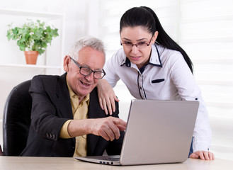 Senior man and young woman looking at laptop