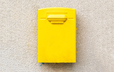 Yellow post office mailbox on plastered wall