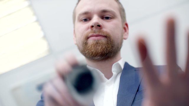 Businessman puts print stamp on office glass table and smile. shoot from below