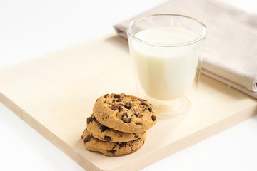 Chocolate chip cookies and a glass of milk on wooden plate
