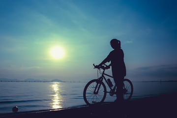 Fototapeta na wymiar Silhouette of healthy biker-girl enjoying the view at seaside