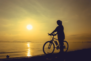 Fototapeta premium Silhouette of healthy biker-girl enjoying the view at seaside