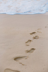 Footprints on the sand with beach foam