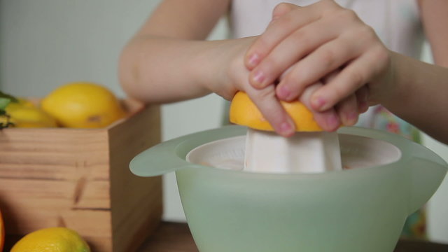 Girl squeezes out juice of a grapefruit, close up