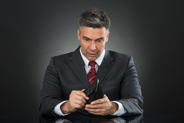 Businessman With Empty Wallet Sitting At Desk