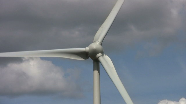 Zoom in to the sails of a wind turbine turning to generate electricity. An alternative renewable energy supply.
