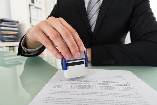 Businessman Using Stamper On Document