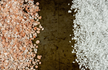 Scattered Himalayan pink salt crystals vs white salt crystals on rusty metal background, space for text
