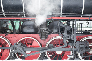 Wheels under locomotive with steam
