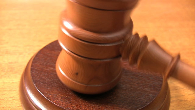 A wooden gavel strikes a sounding block.