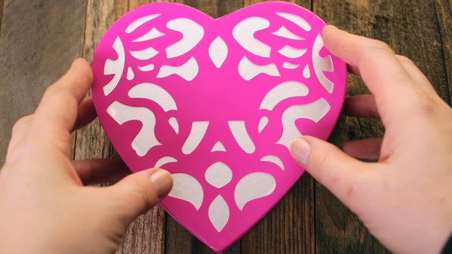 Chocolates in heart shaped box on rustic wood table