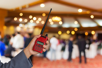 Red radio communication in hand with hall background