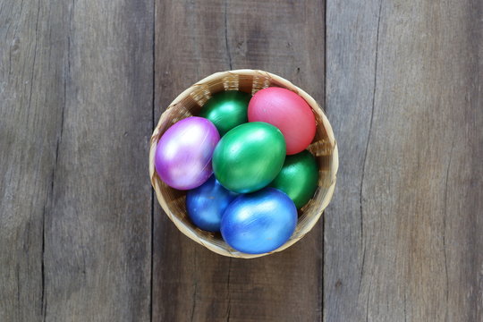 Easter eggs in a wicker basket on wood background.