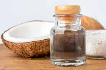 coconut oil in a bottle, background is a half of coconut, isolated