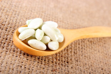 Seeds of beans with wooden spoon on jute canvas, healthy food