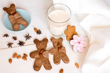 Teddy bear shaped cookies and glass of milk on white wooden table. Homemade sweets for children's holiday or birthday