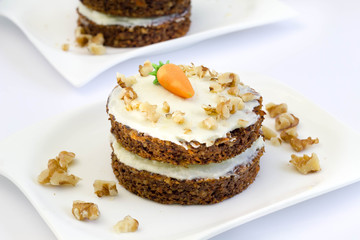 Round mini carrot cakes with cream cheese frosting and marzipan carrot on top.