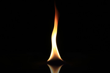 Single burning flame isolated on a black background.
