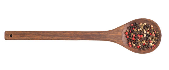 Colored pepper on a wooden spoon isolated on white