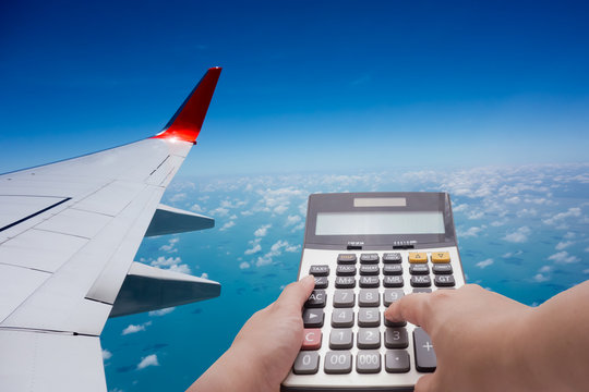 Travel cost calculation concept by calculator and airplane in background