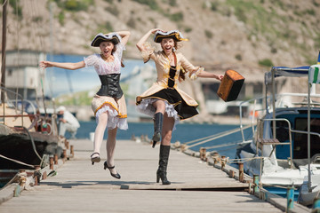 Two girls in pirate costumes are jumping