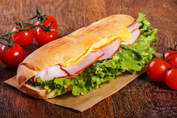 Sandwich from fresh baguette on wooden background