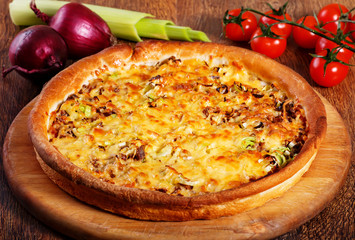 Pizza with beef stuffing, leek and cheese served on wooden table