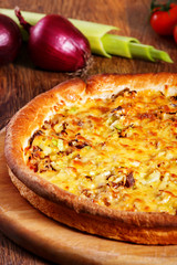 Pizza with beef stuffing, leek and cheese served on wooden table